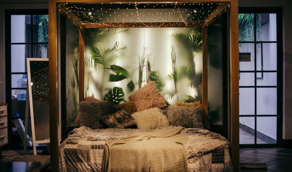 Luxurious modern bedroom with plants and string lights, creating a cozy ambiance.