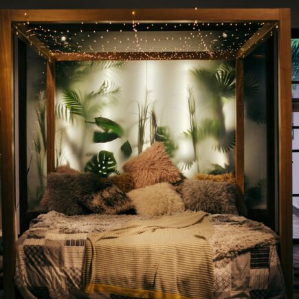Luxurious modern bedroom with plants and string lights, creating a cozy ambiance.